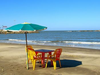 Lifeguard chair on beach against clear blue sky