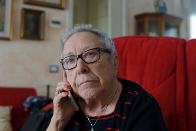 Portrait of woman using phone while sitting on seat at home