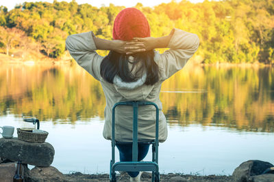 Rear view of young woman standing by lake