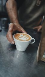 Cropped image of man holding coffee on table