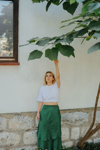 Full length of young woman standing against wall