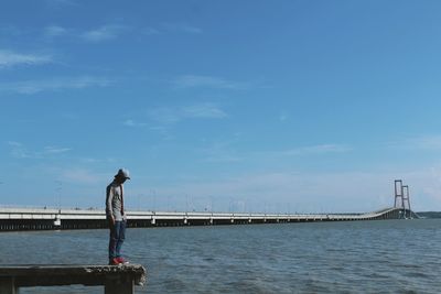 Man standing on bridge over river against sky