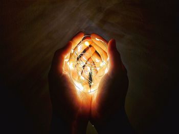 Close-up of hand holding illuminated light bulb