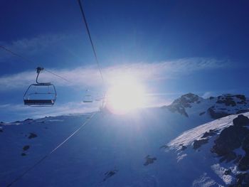 Ski lift over snowcapped mountains against sky