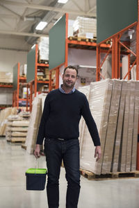 Portrait of confident male customer carrying basket in hardware store