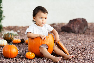 Little toddler girl sitting inside of a big pumpkin 