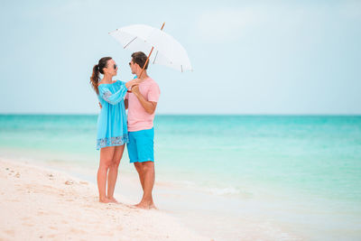 Couple with umbrella standing on beach