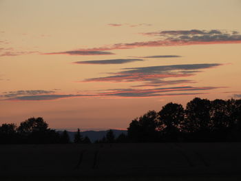 Silhouette trees on landscape against romantic sky at sunset