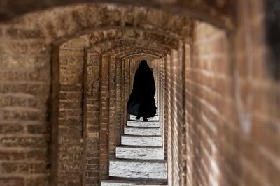 Rear view of woman walking in corridor at historical building