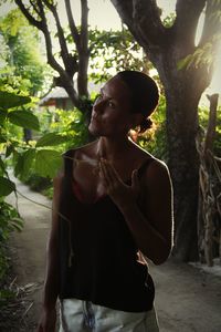 Young woman looking away while standing on tree trunk