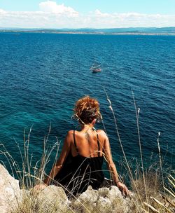 Rear view of woman sitting against sea