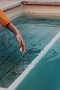 Cropped hand of woman touching swimming pool