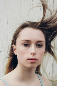 Close-up portrait of young woman against wall