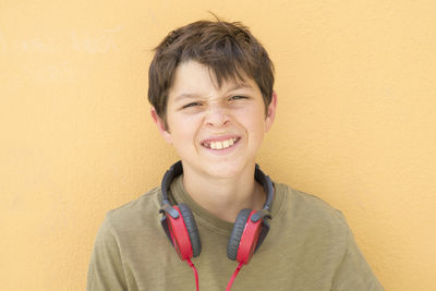 Portrait of boy with headphones against beige wall