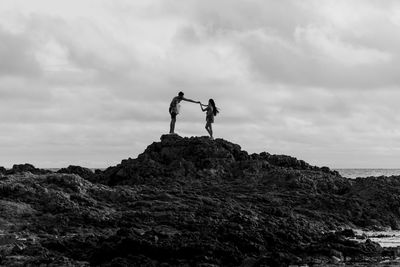 People standing on rock against sky