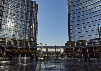 Reflection of modern buildings in city against clear sky