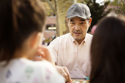 Grandfather playing checkers game while sitting at table in park