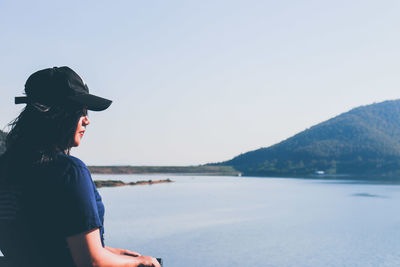 Side view of man looking at lake against sky