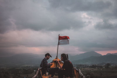 Rear view of men standing on mountain against sky