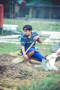Side view of boy sitting on field