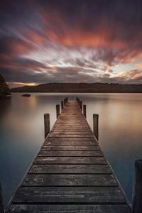 Pier over lake against sky during sunset