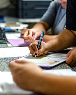 Cropped image of people writing on papers at table