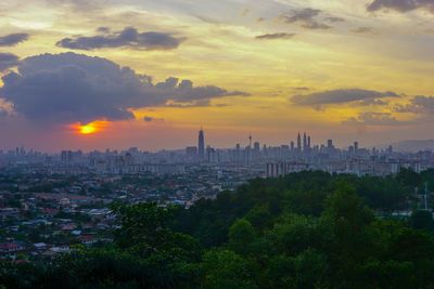 Buildings in city against cloudy sky during sunset