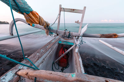 Fishing boat on shore by sea against sky