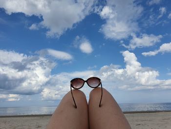 Midsection of woman at beach against sky