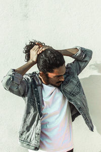 Portrait of young man standing against wall