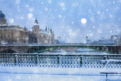 Bridge over river in city during winter