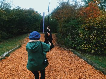 Women enjoying zip line over fallen dry leaves at park