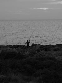 Silhouette of man fishing in sea