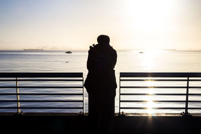 Silhouette woman standing on beach against clear sky during sunset