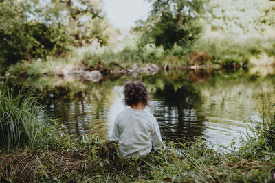 Rear view of child sitting by lake