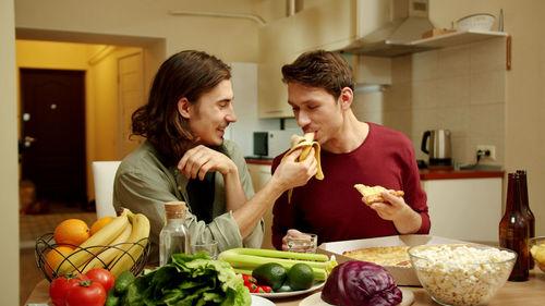 Young couple eating food in kitchen at home