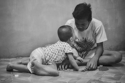 Full length of father and daughter sitting on floor