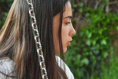 Close-up of woman looking away by metal chain