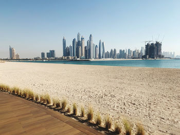 Sea by modern buildings against clear sky