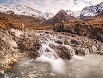 Stream flowing through rocks against mountains