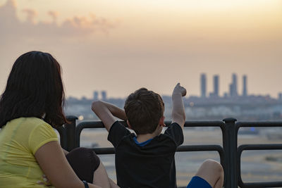 Mother and child looking at madrid city skyline  during sunset.