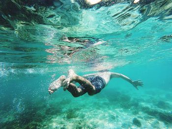 Full length of shirtless man swimming in sea