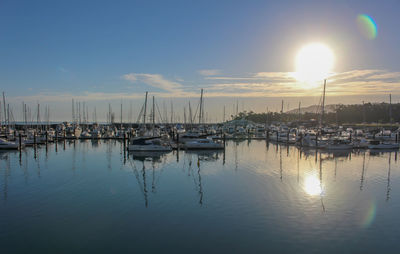 Sailboats moored in marina at sunset