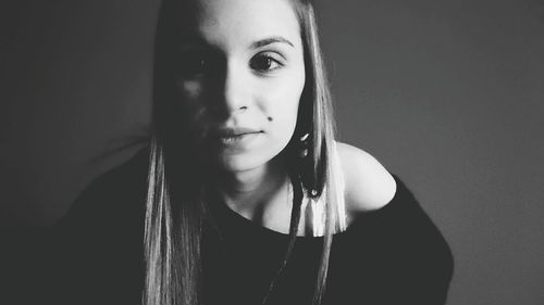 Close-up portrait of a young woman against black background