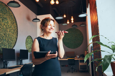 Young woman using mobile phone while sitting in cafe