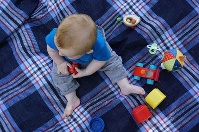 High angle view of baby boy playing with toys on blanket