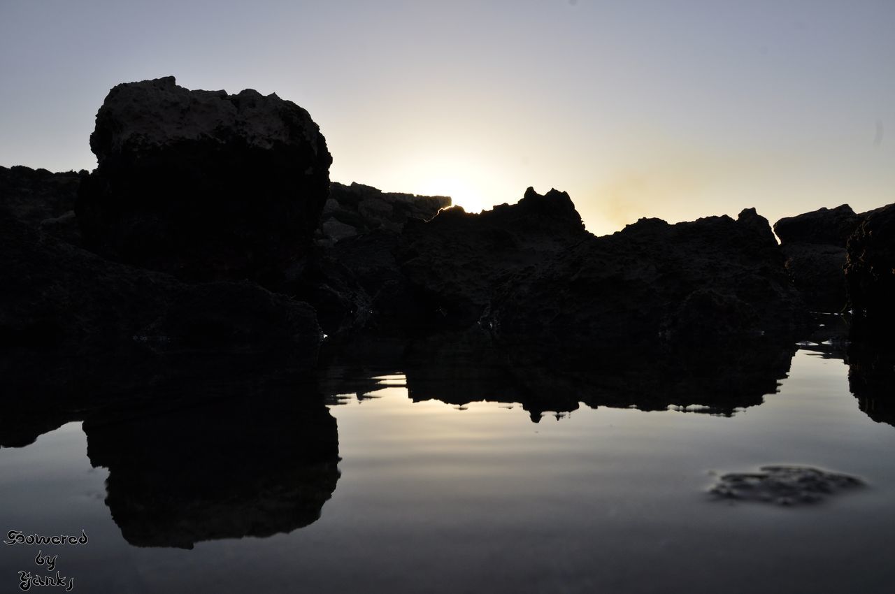 water, tranquility, tranquil scene, rock formation, scenics, reflection, rock - object, beauty in nature, clear sky, nature, waterfront, sunset, idyllic, sea, sky, rock, cliff, silhouette, geology, copy space