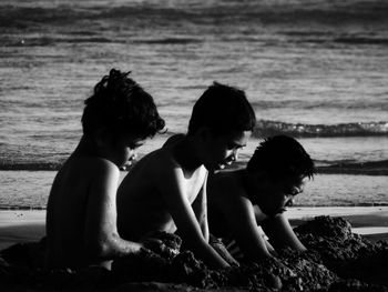 Rear view of people sitting on beach