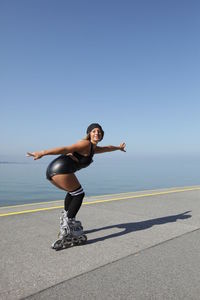 Woman inline skating on road by sea