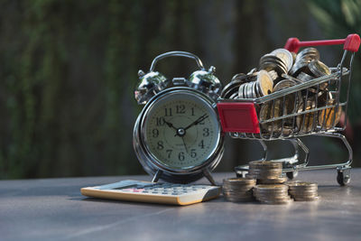 Close-up of alarm clock and coins on table